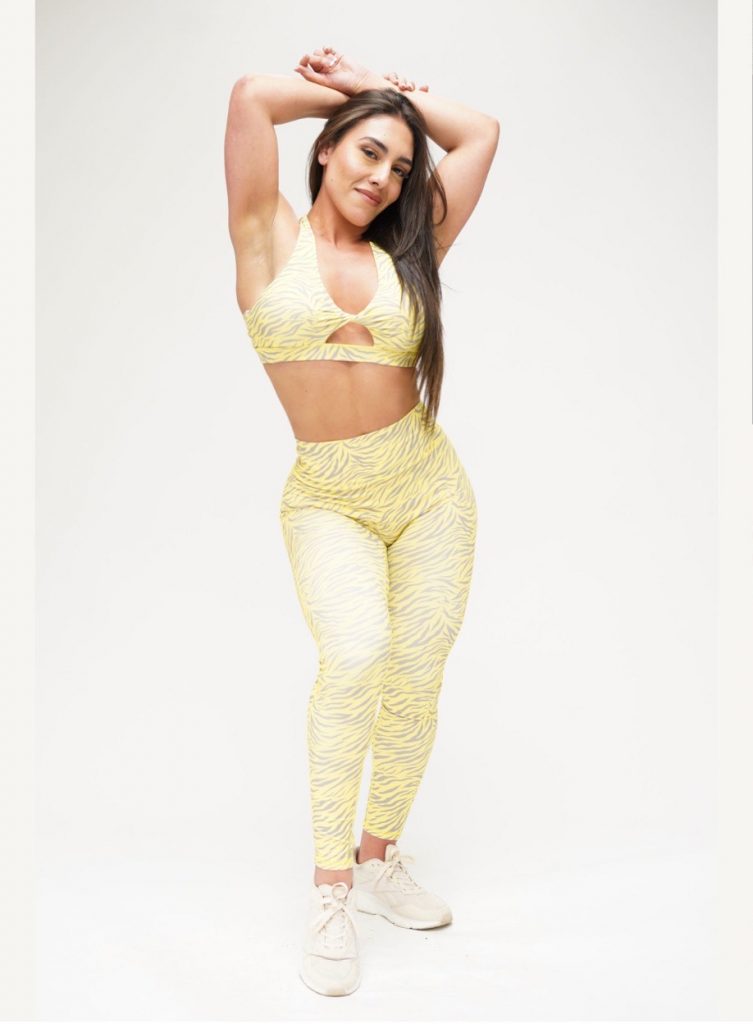 Gera, founder of CoraZONE Fitness, posing confidently in yellow activewear, embodying strength and grace.